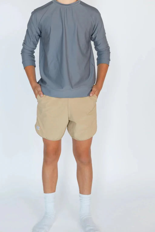 Person wearing a gray long-sleeve shirt and beige shorts on a white background