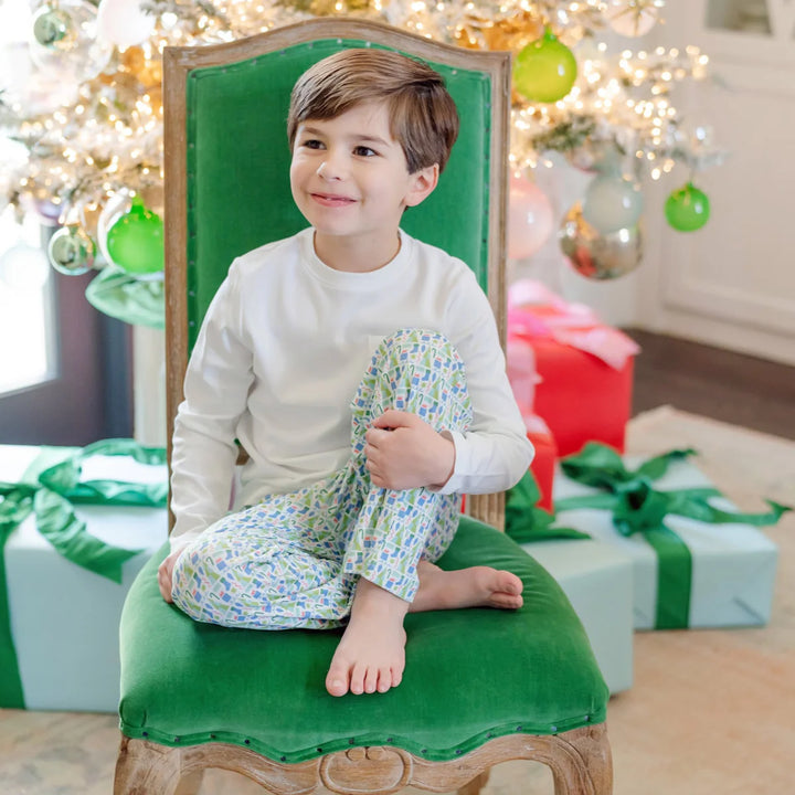 Child sitting on a green stool in front of a decorated Christmas tree with presents.