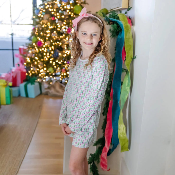 Young girl in a festive setting with a decorated Christmas tree and colorful ribbons.