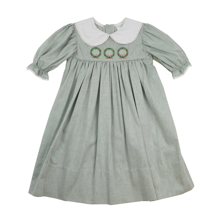 Green dress with white collar and embroidered details on a white background