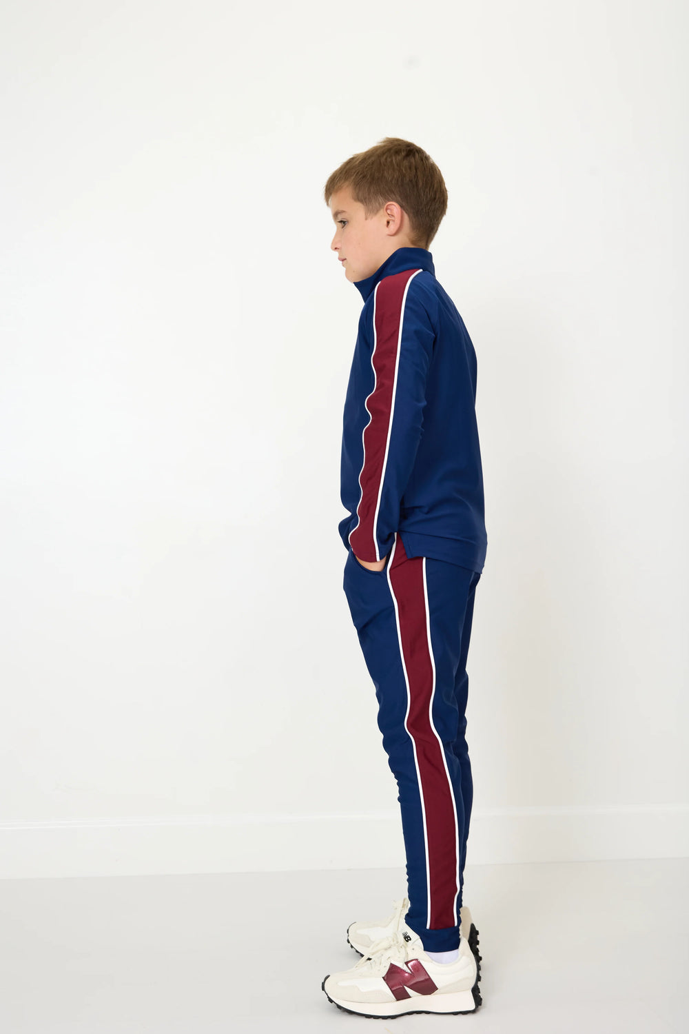 Child wearing a blue tracksuit with red stripes on a white background
