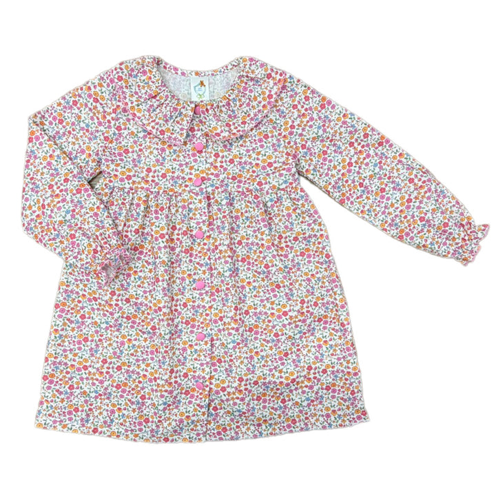 A long-sleeve baby dress with a dense multicolor floral print on a white background, featuring a ruffled Peter Pan collar and pink buttons.