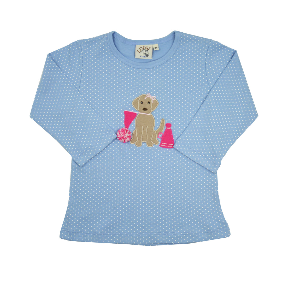 A light blue long-sleeve t-shirt with white polka dots, featuring an applique design of a tan puppy holding pink pom-poms on the chest. The shirt is displayed flat against a solid white background.