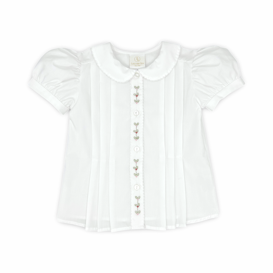 A white short-sleeve baby blouse with a Peter Pan collar, vertical pleats, and decorative embroidered details down the front center.