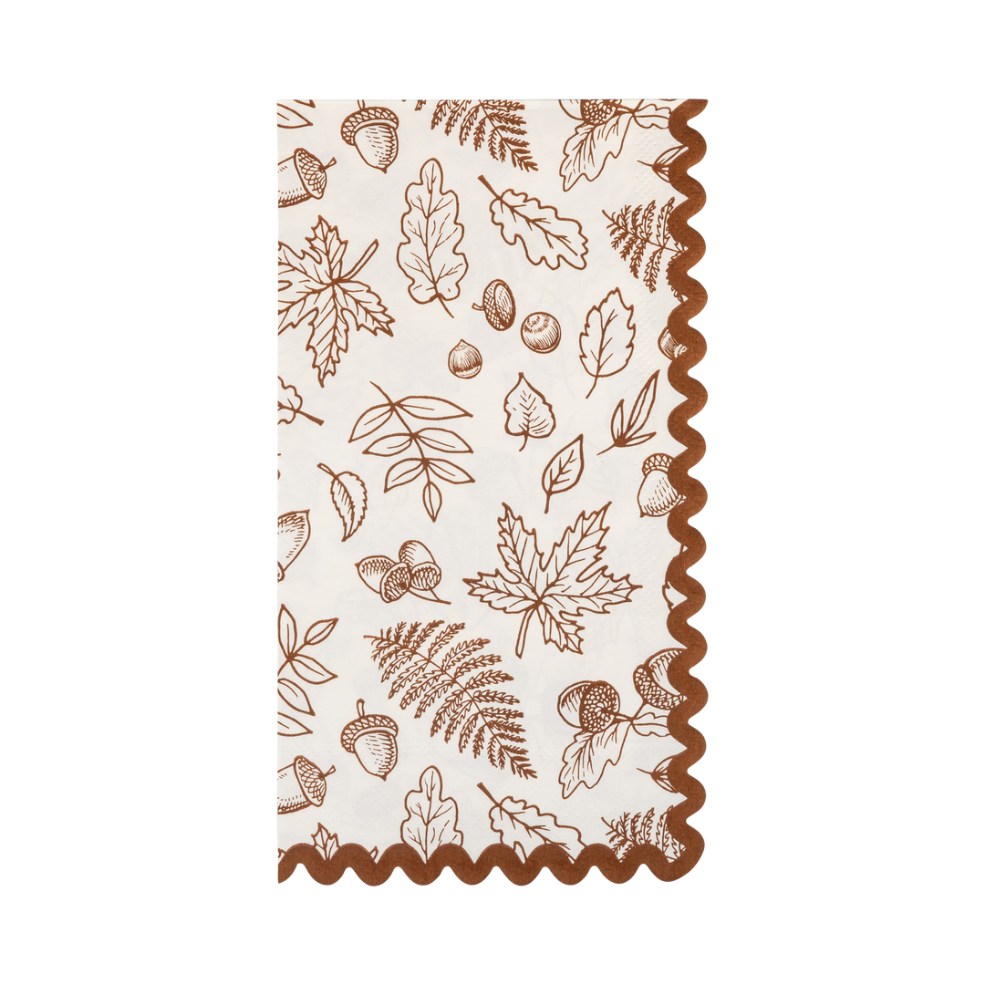 A rectangular cream-colored napkin with a brown autumn-themed print of leaves, acorns, and ferns, finished with a wavy brown scalloped edge.