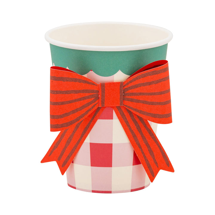 Paper cup with a red and white checkered design and a large red bow on a white background