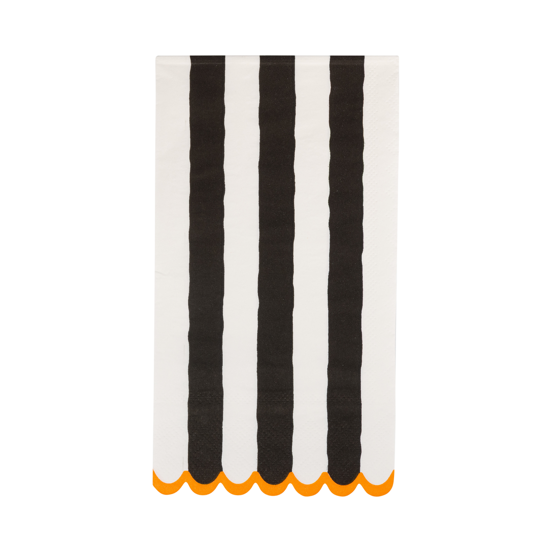 A rectangular white fabric item, likely a napkin or small towel, featuring four bold vertical black stripes and a scalloped orange edge along the bottom, shown against a plain white background.