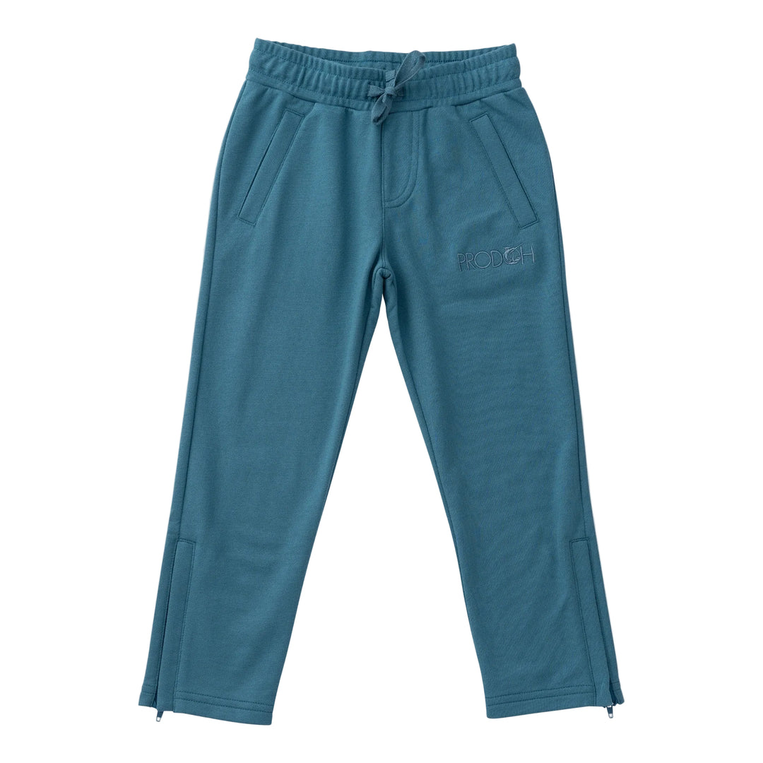 A pair of teal blue sweatpants with an elastic drawstring waist, side pockets, and a subtle embroidered logo on the left thigh, shown against a light beige background.
