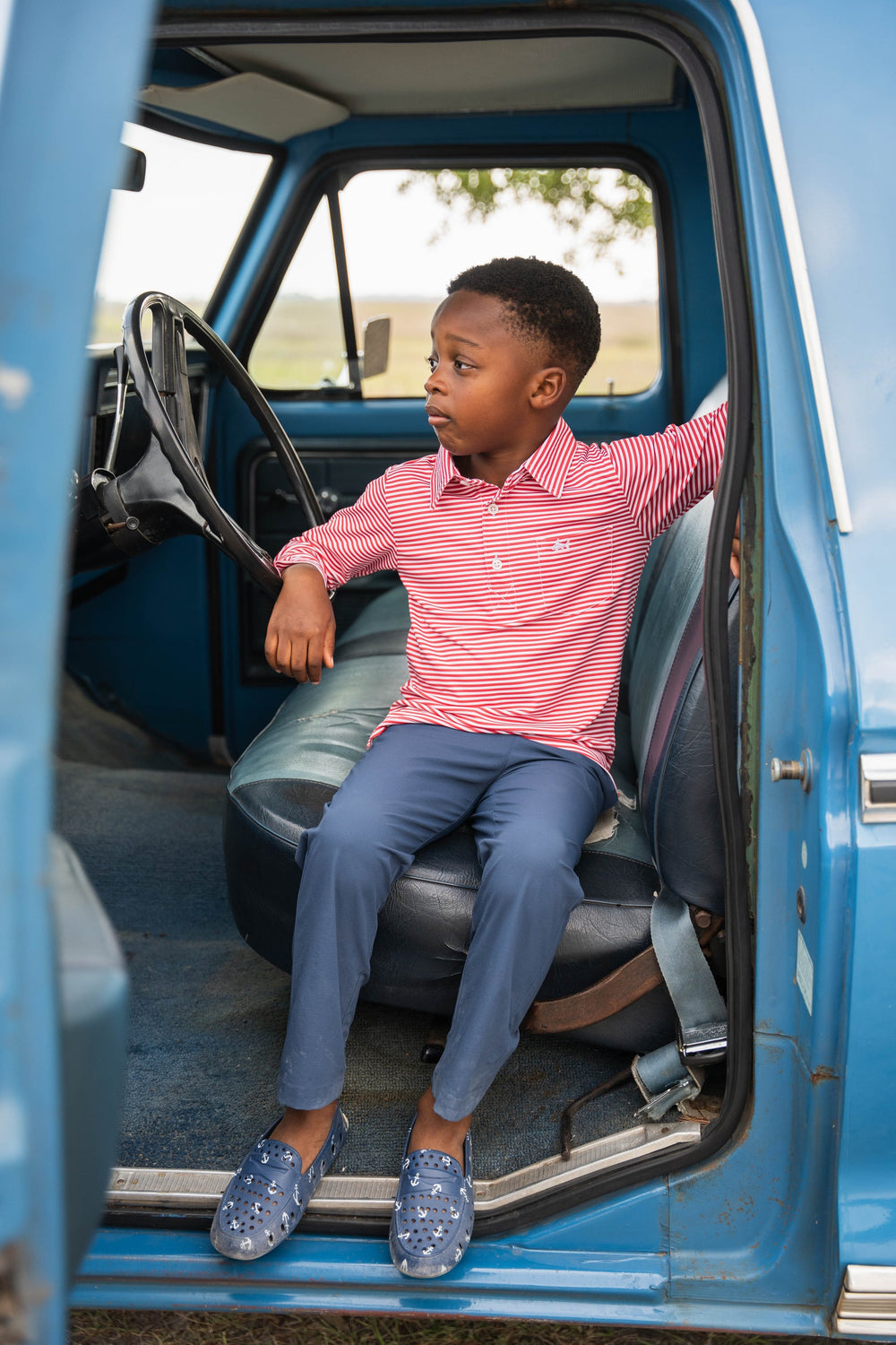 Child sitting inside a blue truck with open door