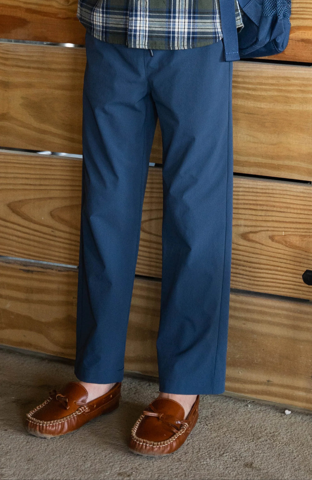 Person wearing blue pants and brown shoes standing in front of a wooden dresser.