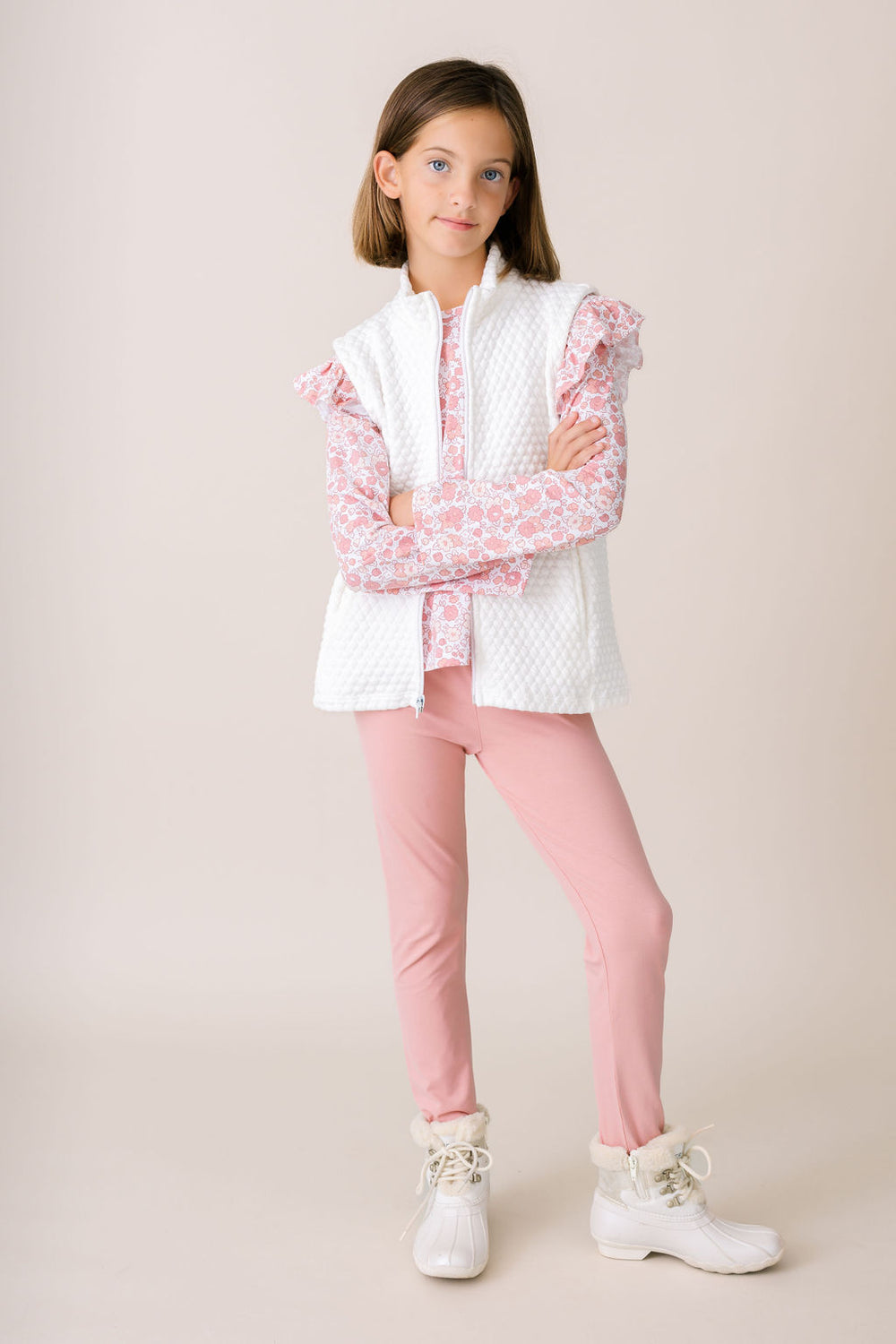 Young girl wearing a pink and white outfit with a white background