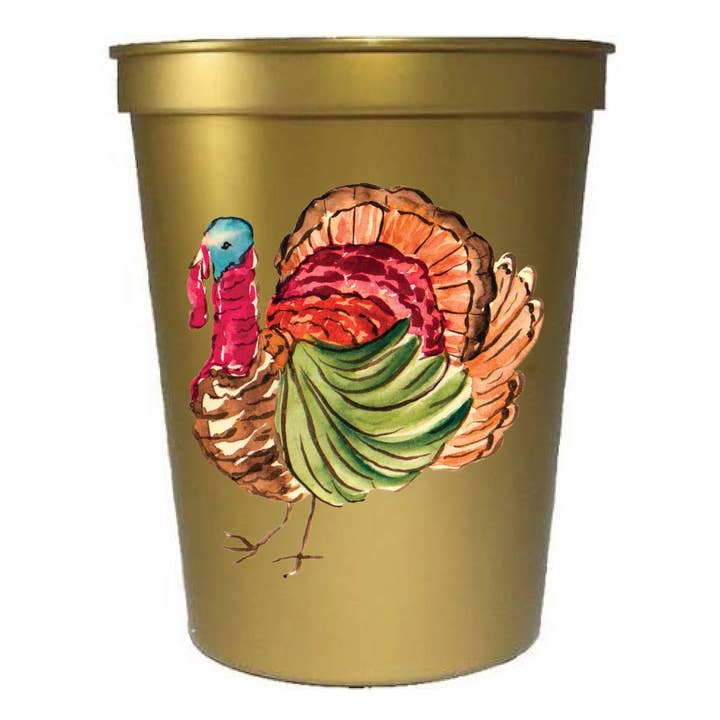 A gold-colored plastic party cup featuring a colorful printed illustration of a turkey on the front, set against a plain white background.