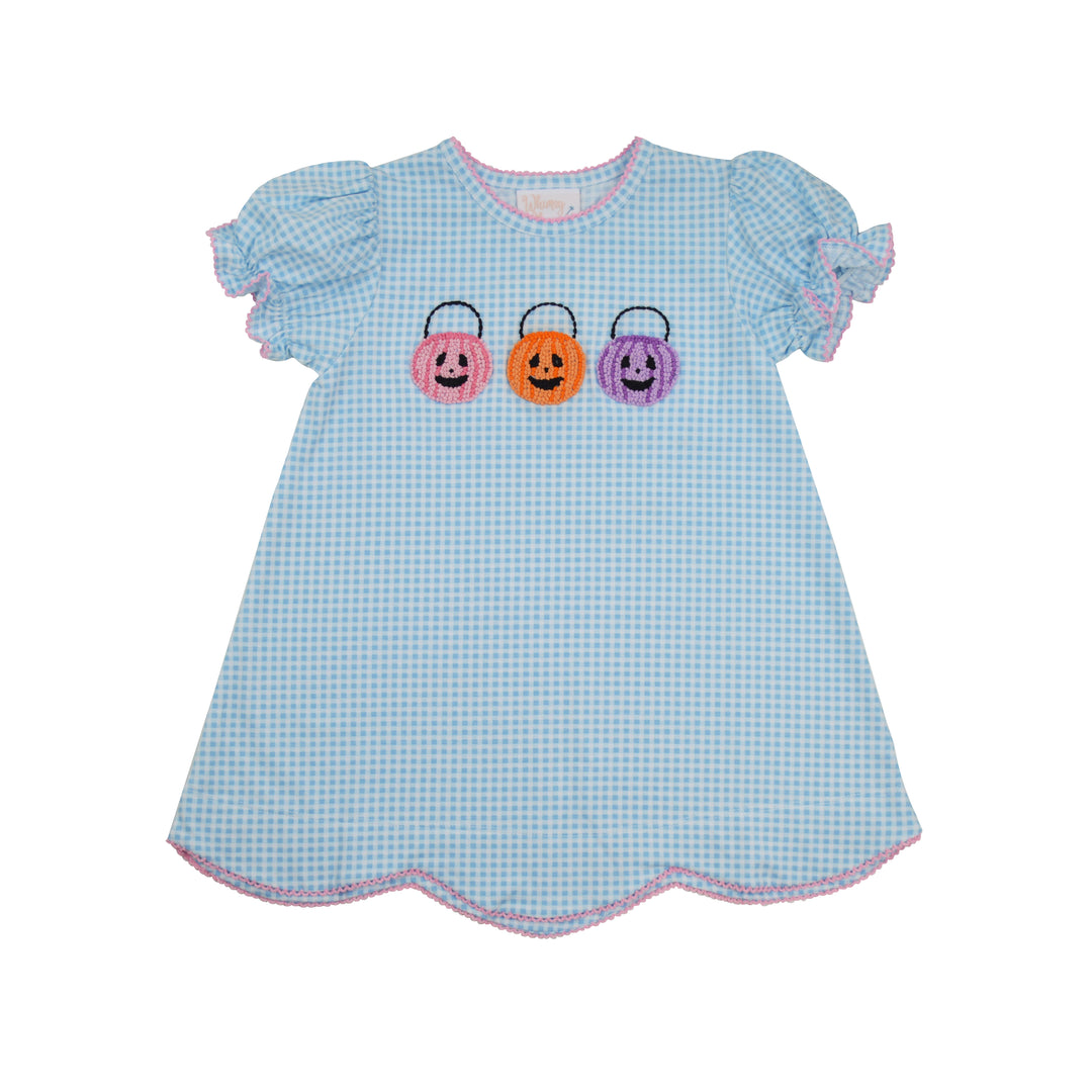 A light blue and white gingham dress for toddlers, featuring three embroidered Halloween candy baskets in pink, orange, and purple across the chest, with ruffled sleeves and a scalloped hem.