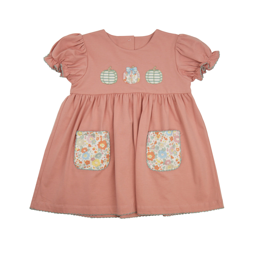 A toddler's short-sleeve dress in dusty rose pink, featuring three embroidered pumpkin motifs on the chest and two floral patterned patch pockets on the front.
