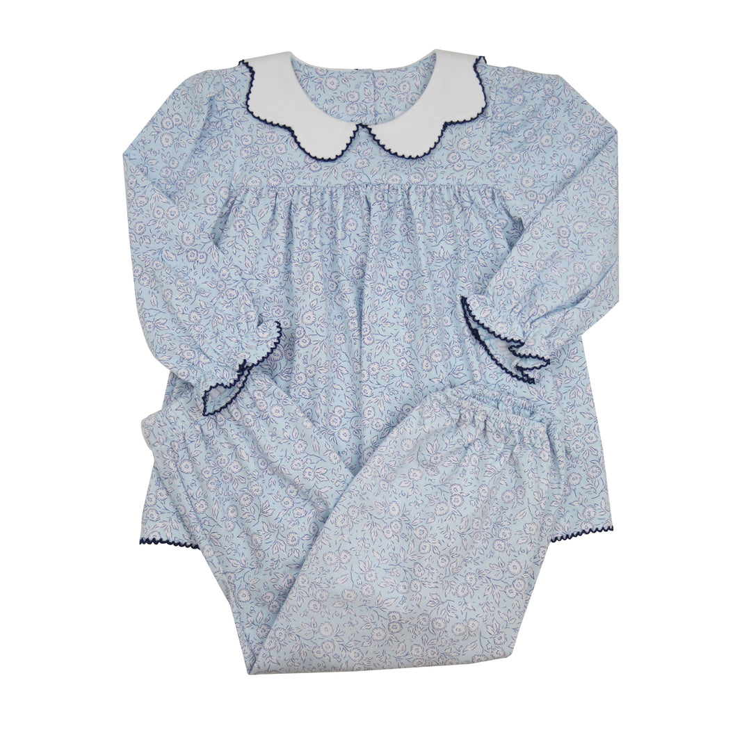 A baby girl's two-piece set in a light blue and white floral print. The long-sleeve nightgown features a white Peter Pan collar with dark blue trim, and the matching bloomers have an elastic waist and leg cuffs with dark blue trim.