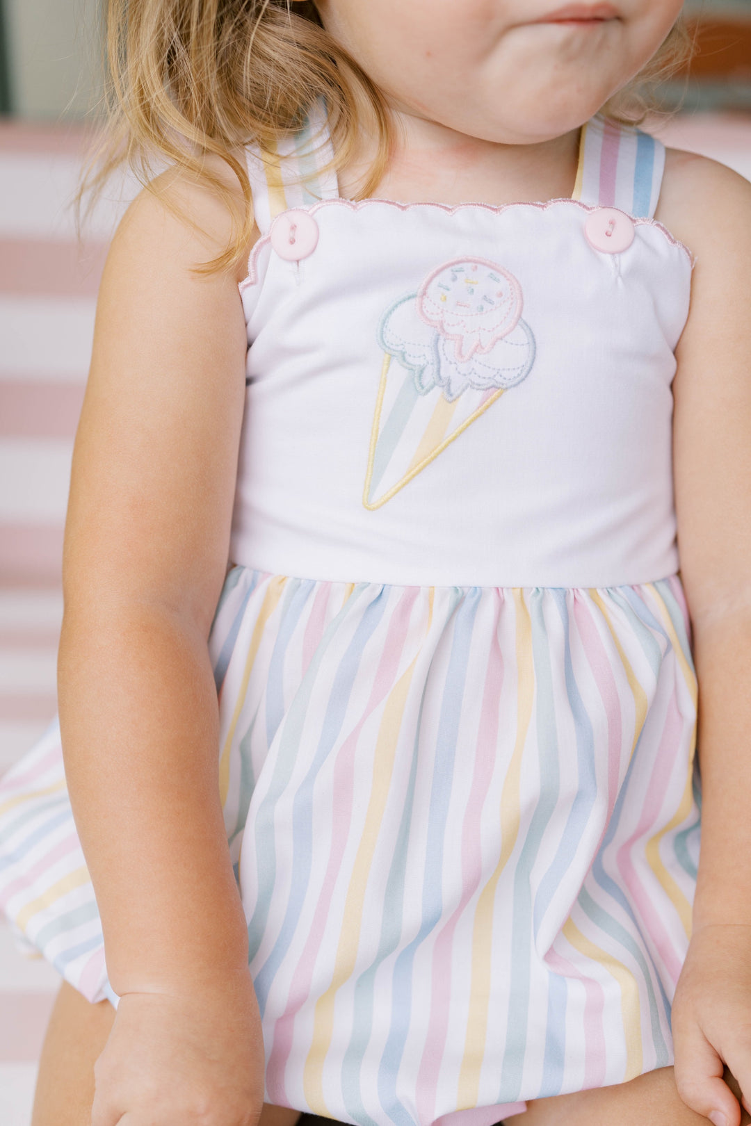 Child wearing a sleeveless top with ice cream cone design and a striped skirt.